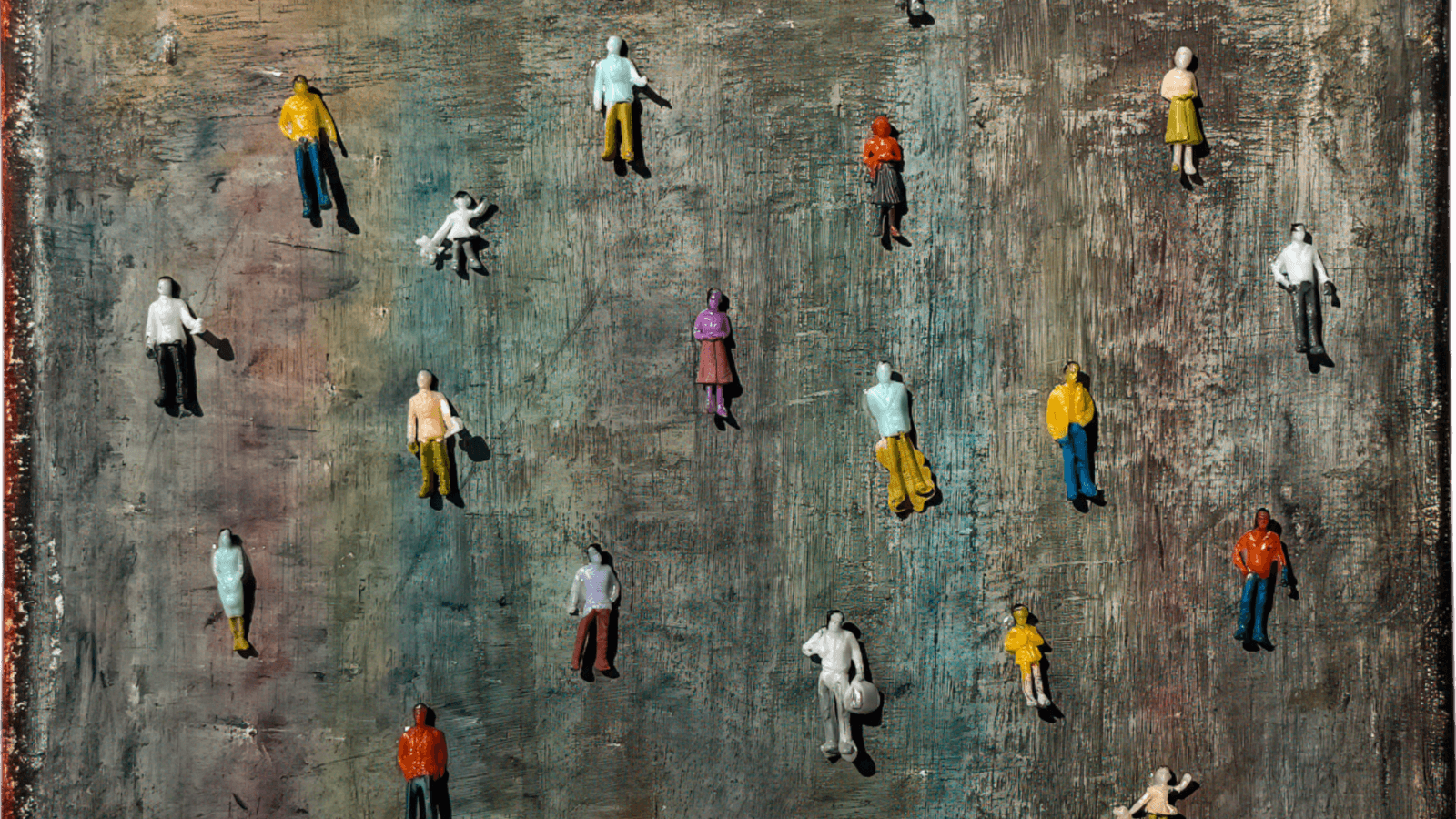 Colorful miniature figures scattered on a textured background, representing diversity in figurative art.