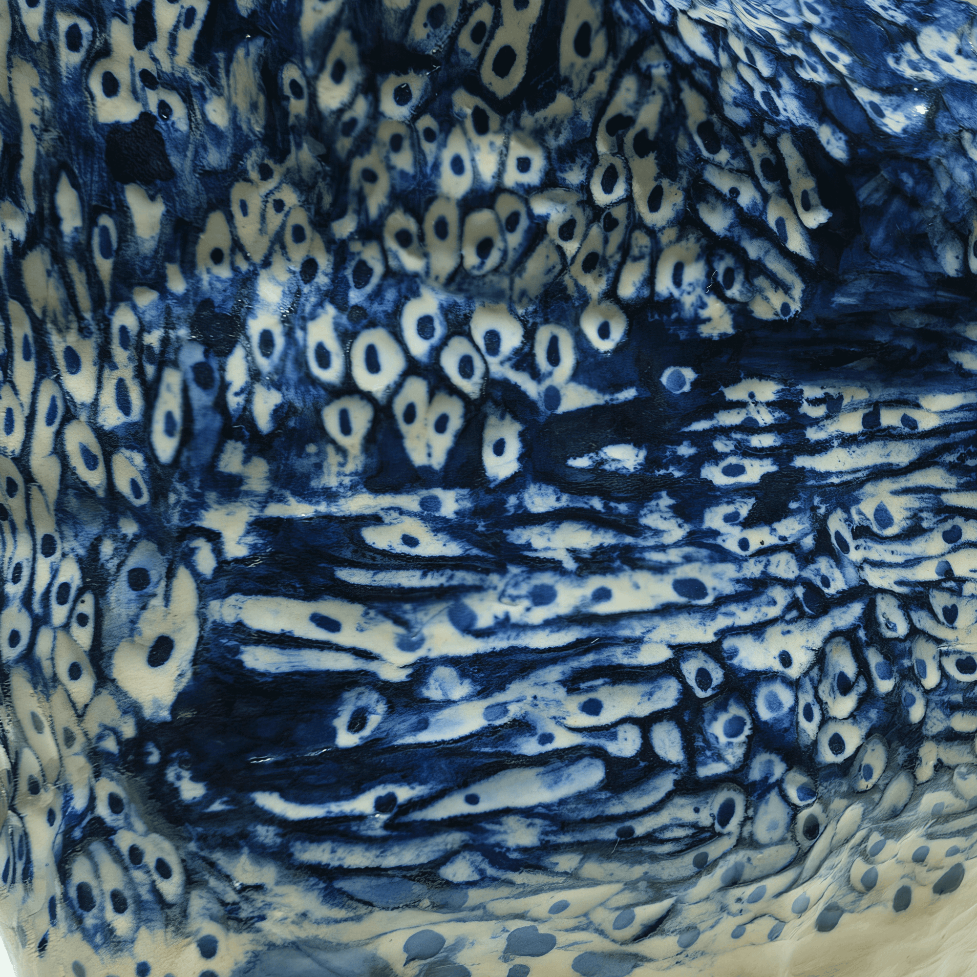 Close-up of intricate cobalt oxide patterns on a hand-sculpted ceramic artwork by Supmanee Chaisansuk.