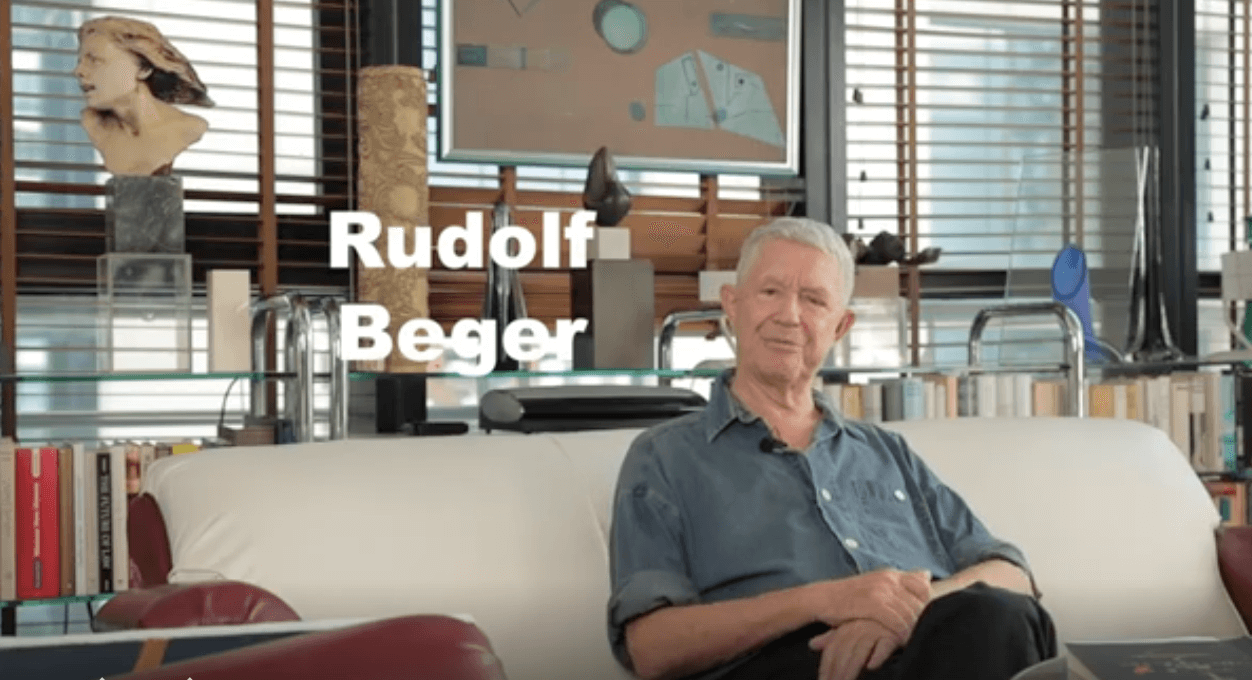 Rudolf Beger sitting on a white sofa in an art-filled room