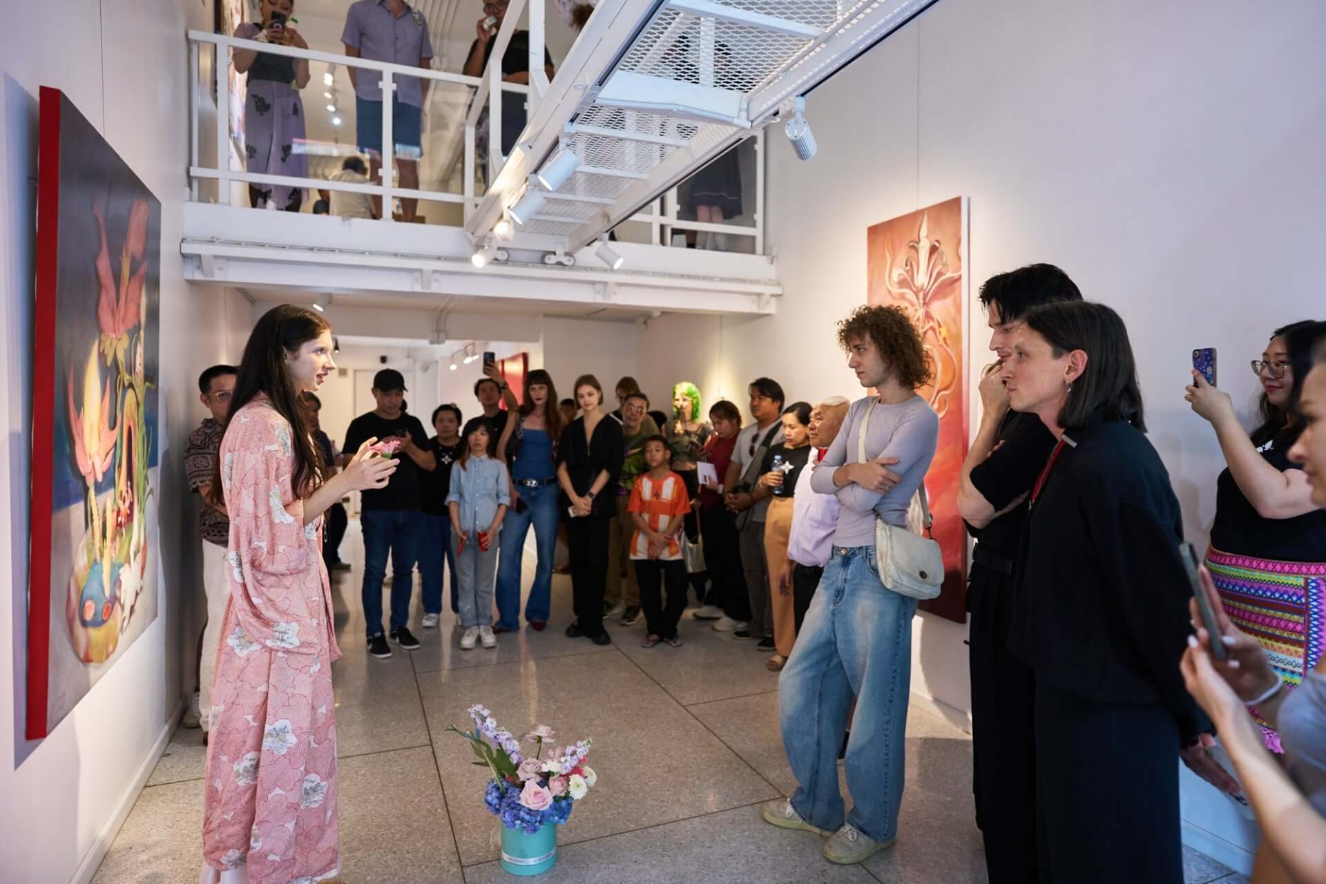 Gallery tour with an artist speaking to an engaged audience in a modern art exhibition space.