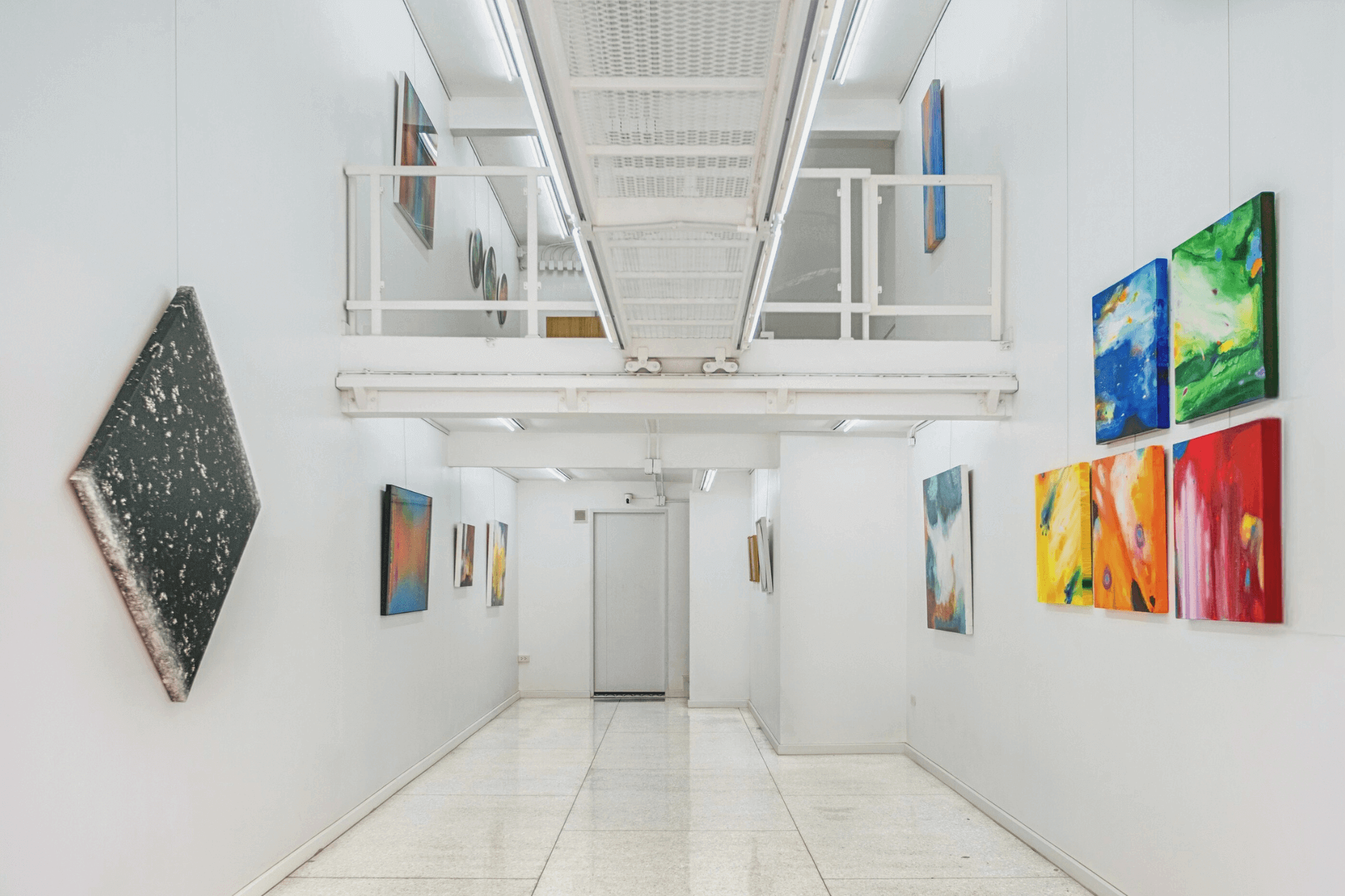 Art gallery hallway featuring colorful paintings on white walls, showcasing contemporary artwork and modern design.