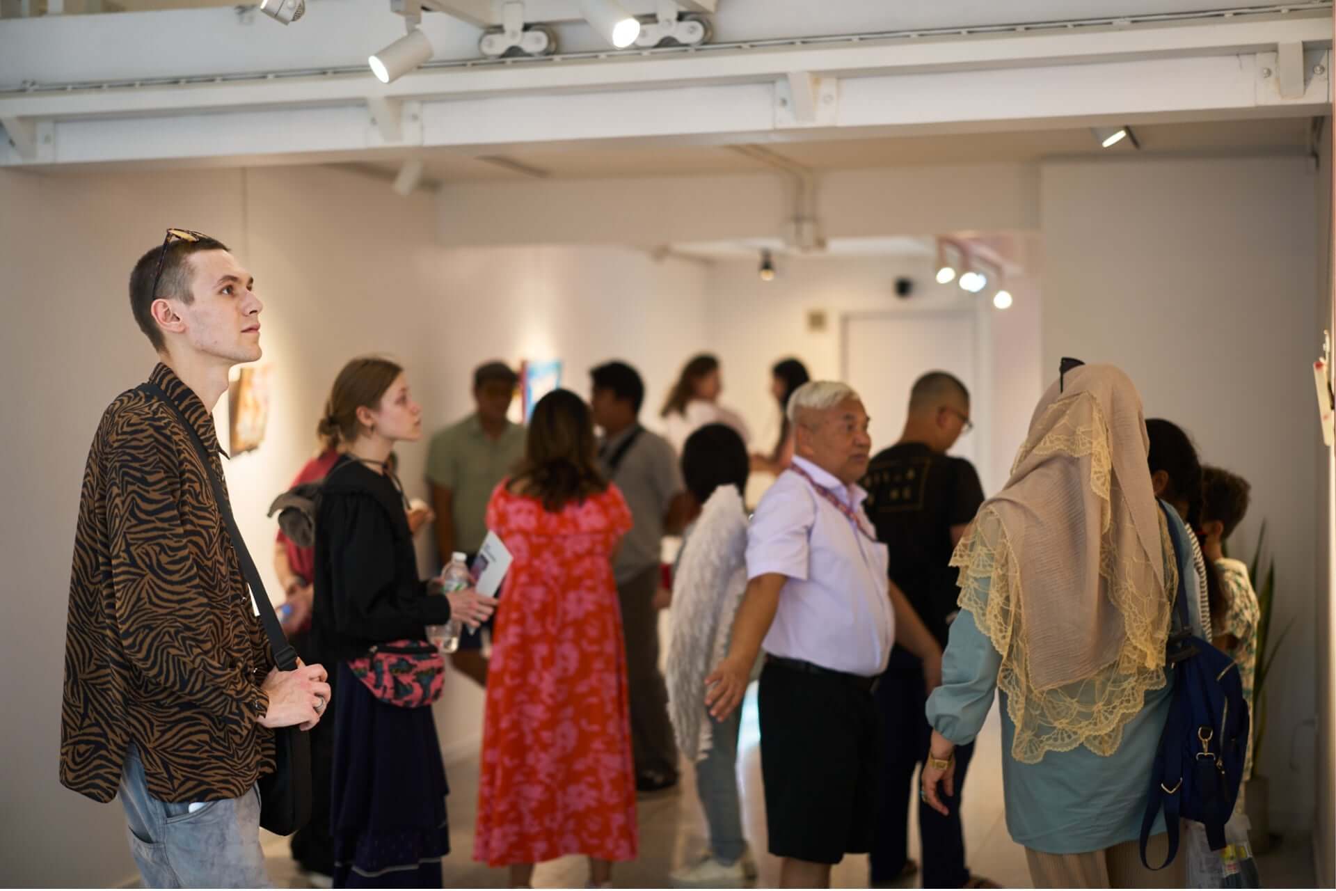 People enjoying an art exhibition in a gallery setting.