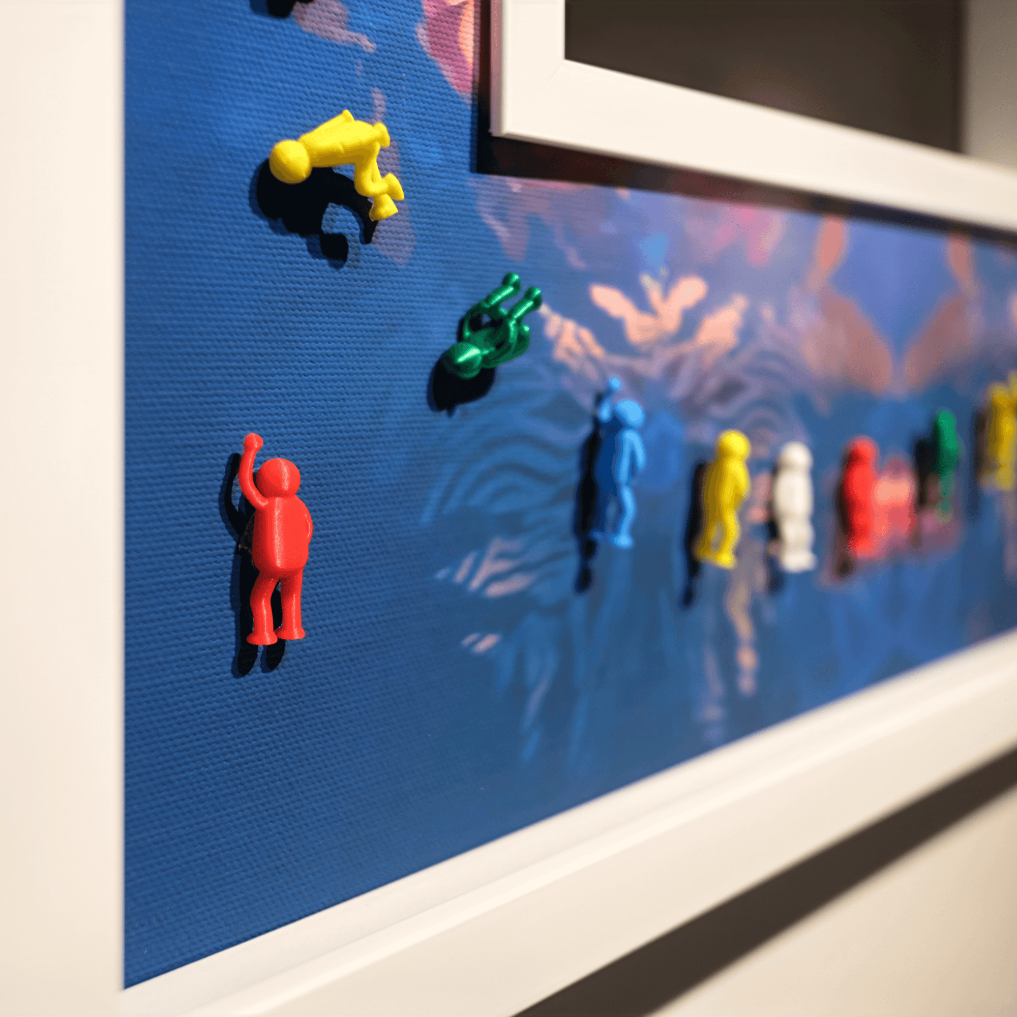 Colorful plastic figures climbing on a blue textured backdrop, showcasing creativity and design in an artistic setting.