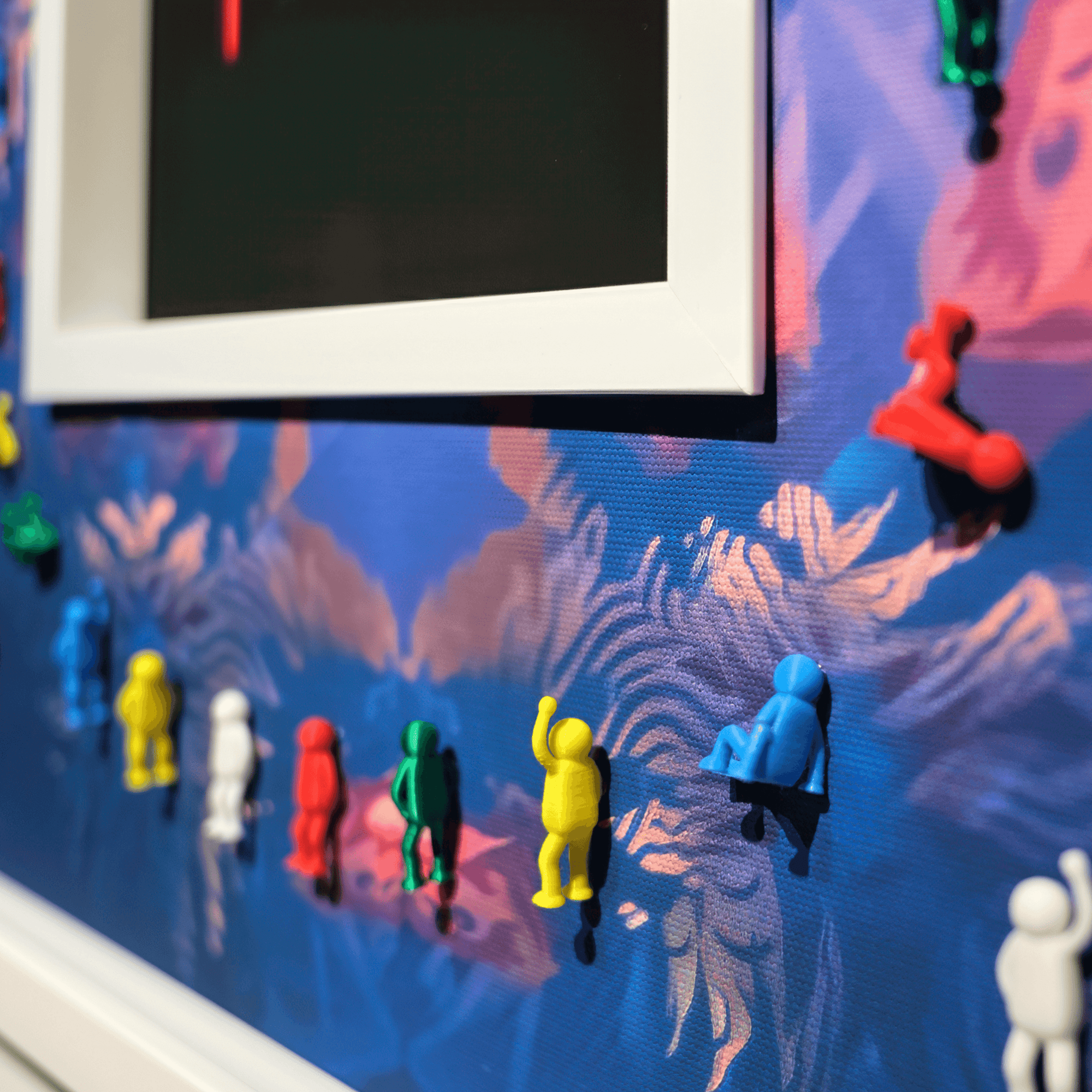 Colorful mini figures attached to a wall art piece, showcasing an artistic background with vibrant colors.