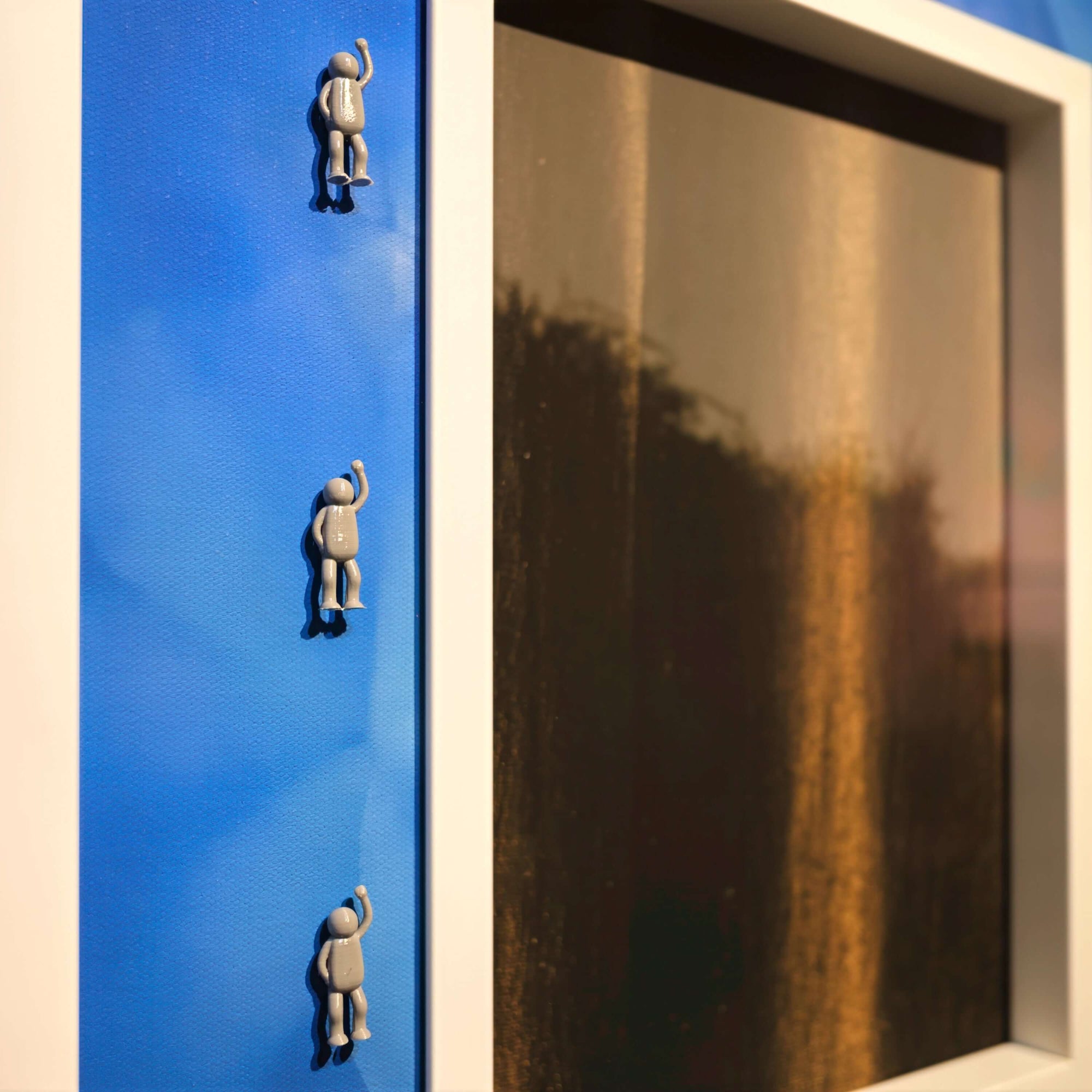 Rhythm of the Frame, 2025 art piece featuring miniature figures climbing a blue frame next to a dark panel.