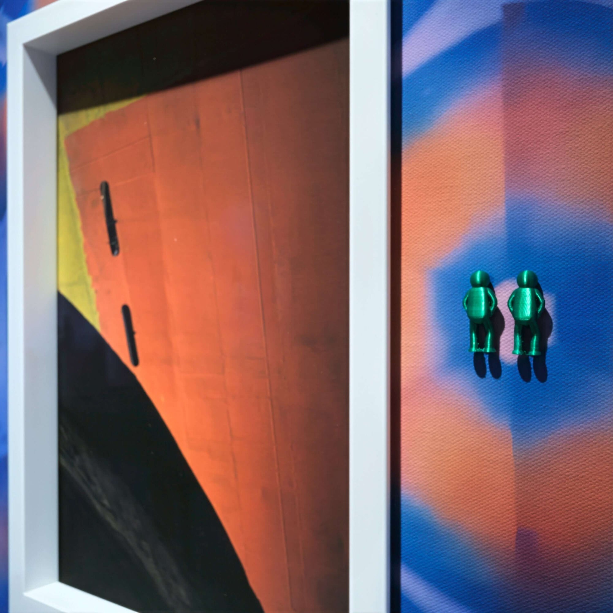 Artwork featuring a colorful abstract background and two green figures alongside a framed piece titled 'Spiral Inward, 2025'.