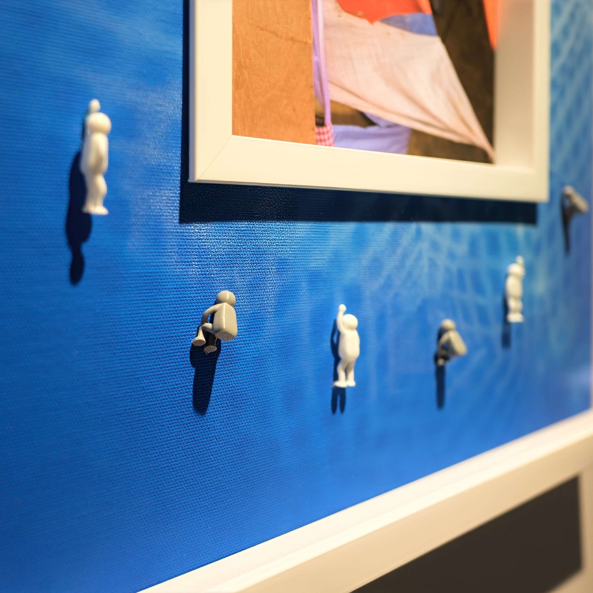Covered Memory, 2025 - wall art with small figurines against a blue background, showcasing creative decor and design.