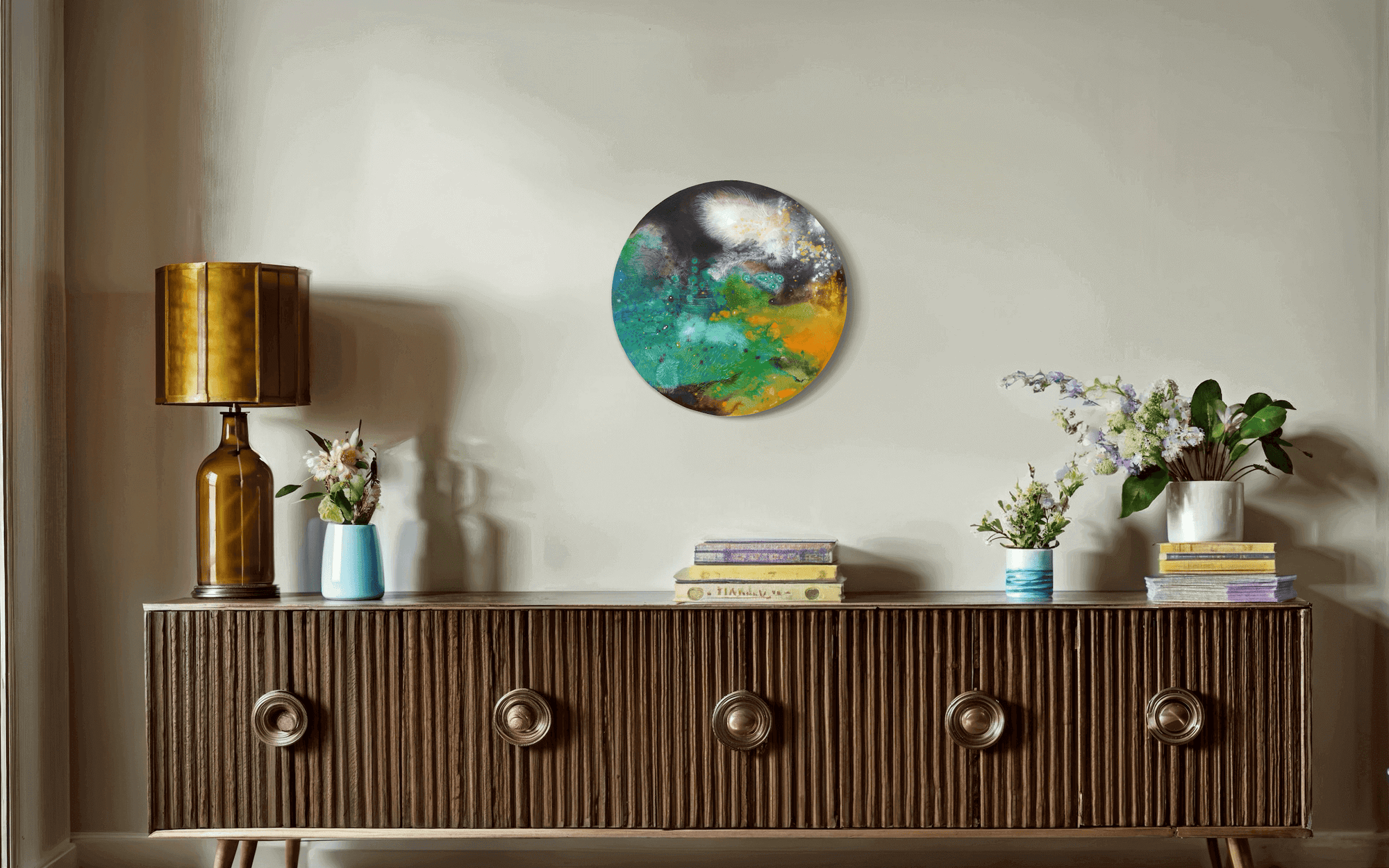 "Abstract round painting by Thai artist Supmanee Chaisansuk on wall, contemporary landscape with fluorescent colours, above wooden sideboard"