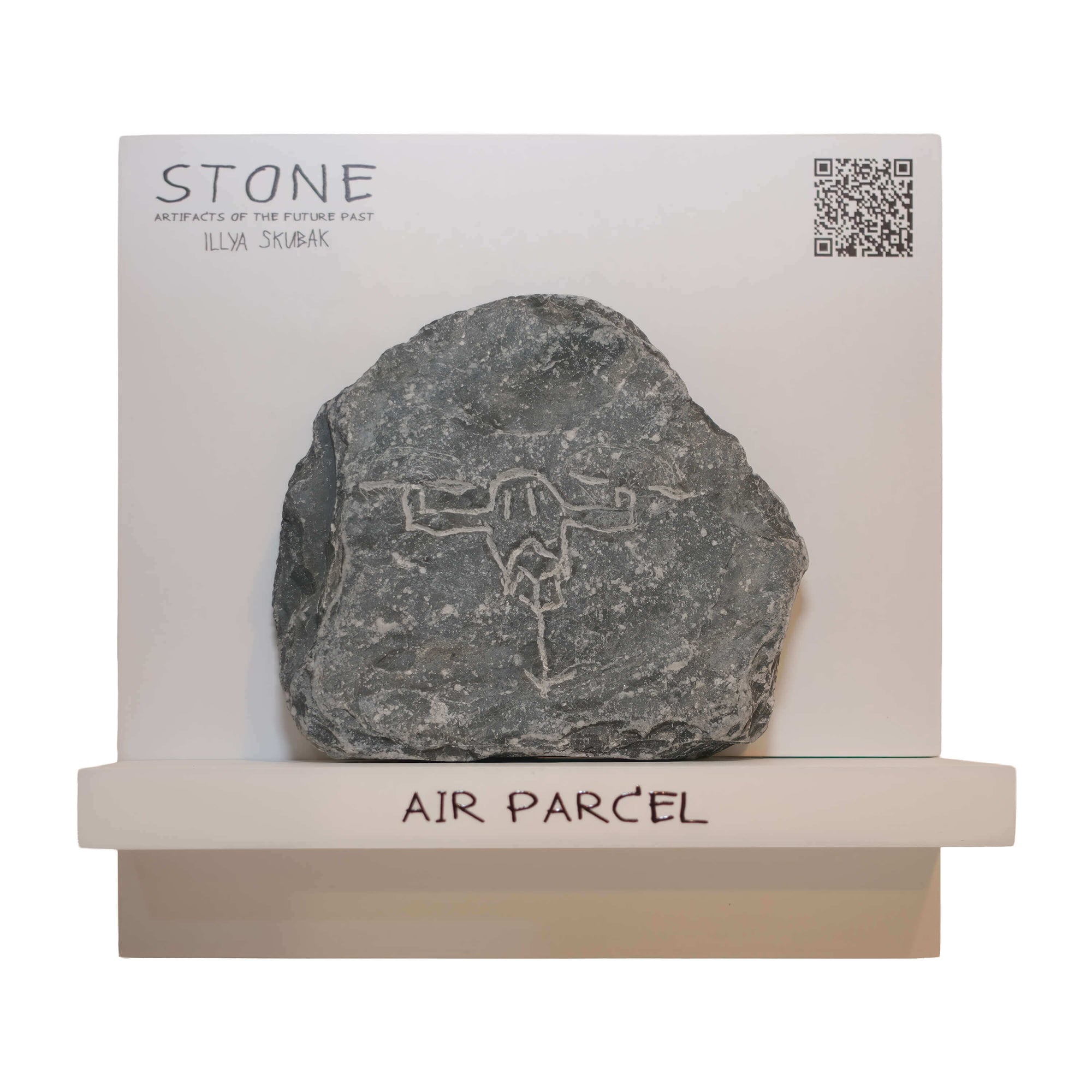 A unique stone art piece titled 'AIR PARCEL' by Ilya Skubak, featuring engraved symbols, displayed on a minimalist shelf.