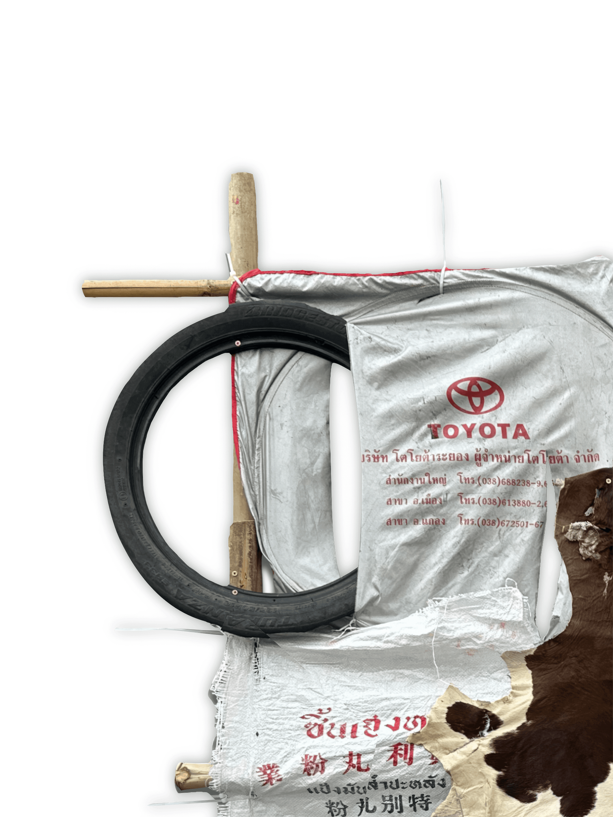 Artistic composition featuring a black tire, wrapped materials, and a Toyota logo, showcasing texture and contrast.