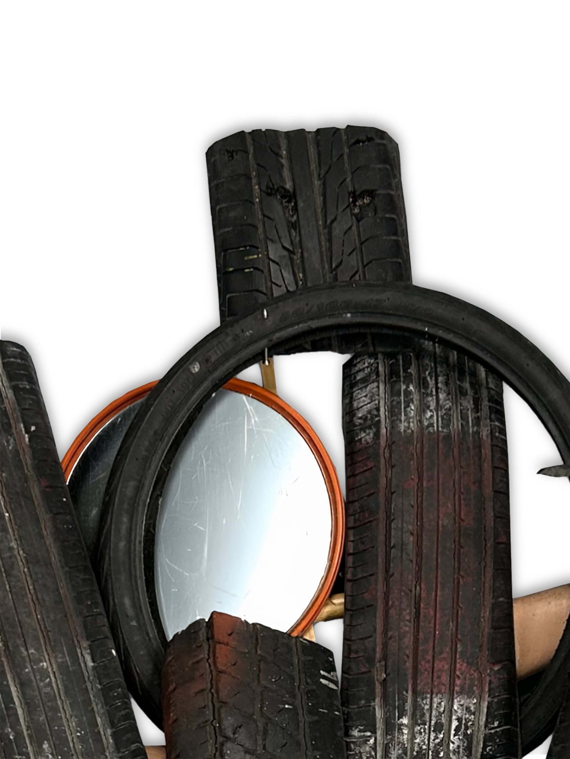 Stack of worn-out tires with a reflective surface, showcasing various tread patterns and textures.