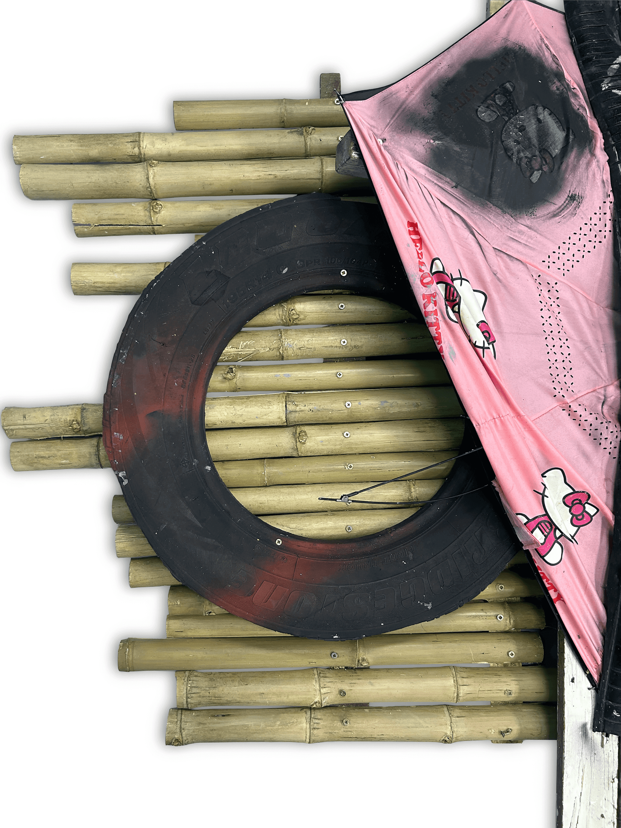 A circular tire hanging against a bamboo wall, partially covered by a pink fabric with a playful design.