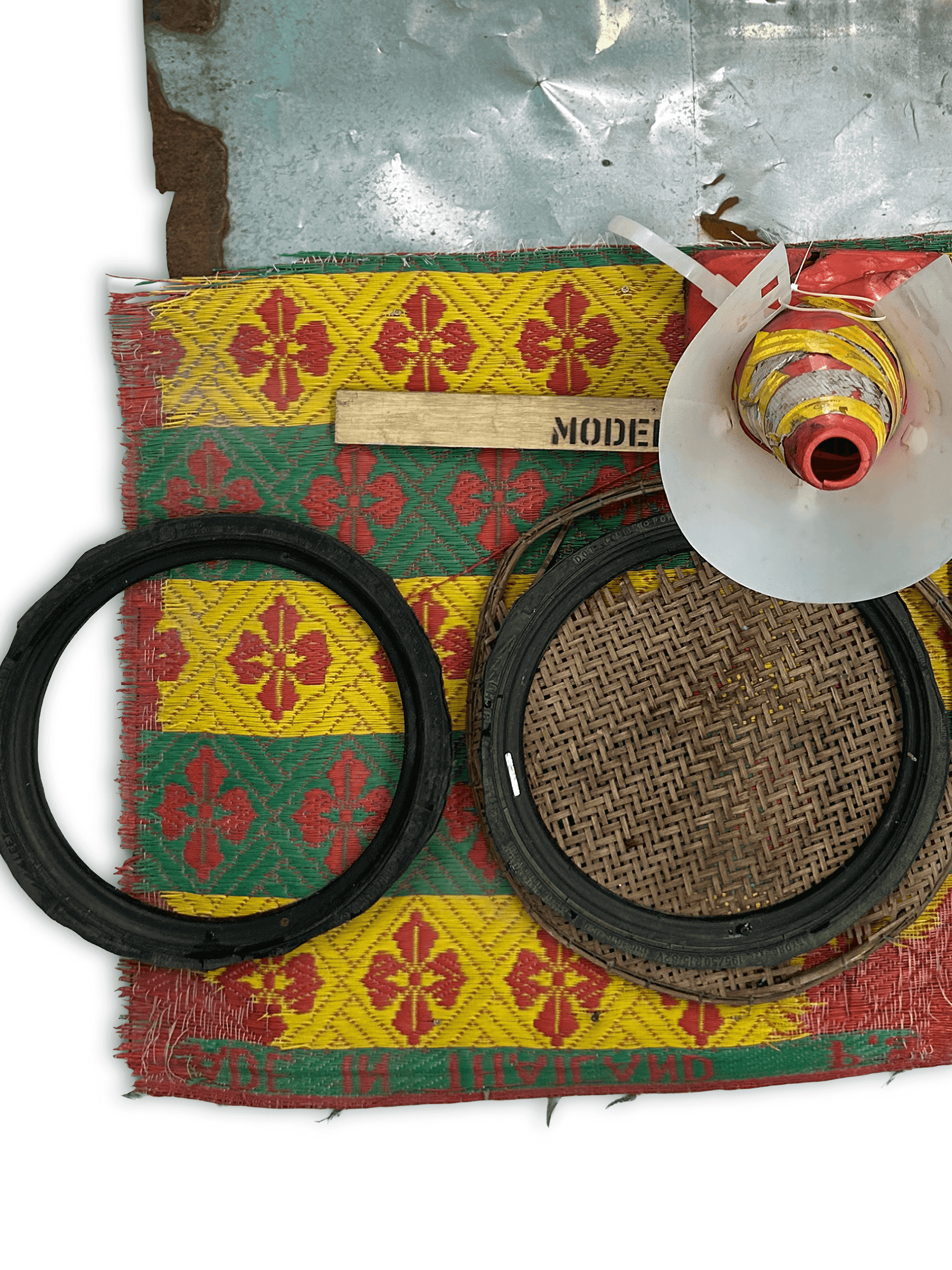 Artistic arrangement of traditional crafting materials including woven baskets, rubber rings, and colorful patterned fabric.