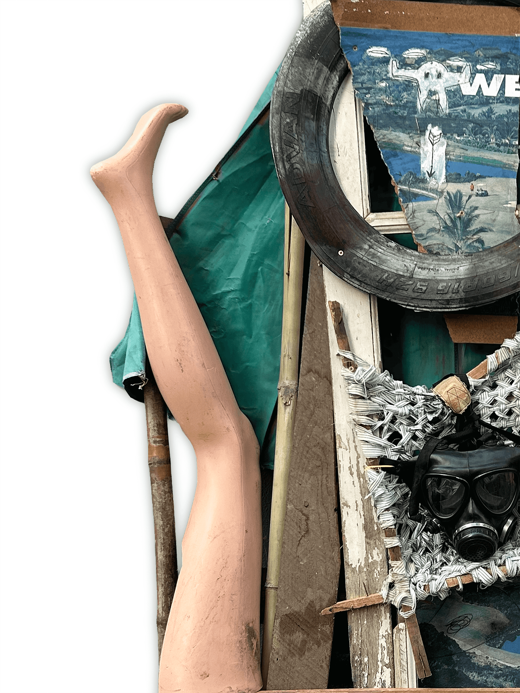 A whimsical arrangement of objects, featuring a mannequin leg, tires, wood, and a gas mask, set against a green backdrop.